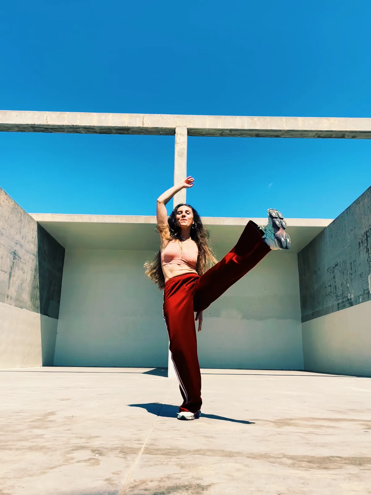 Elisabet Solo bailando con la pierna en alto sobre una azotea, con el cielo azul de fondo