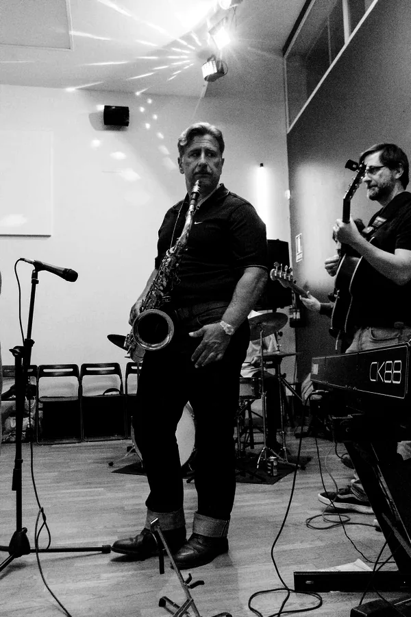 Saxofonista tocando con la banda en directo durante una sesión, en blanco y negro