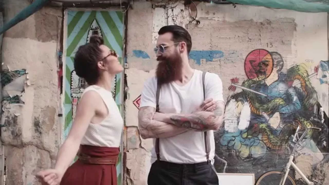 Fotograma del cortometraje Mouet: dos personas frente a un muro con grafitis