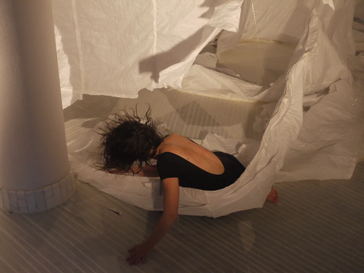 Elisabet Solo tendida sobre plásticos blancos durante la performance Ópera de paper