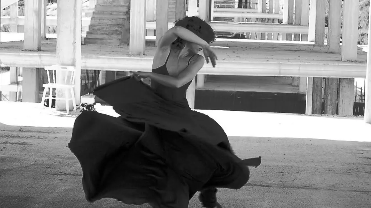 Elisabet Solo girando con vestido negro entre los pilares de hormigón de un edificio sin terminar, en blanco y negro